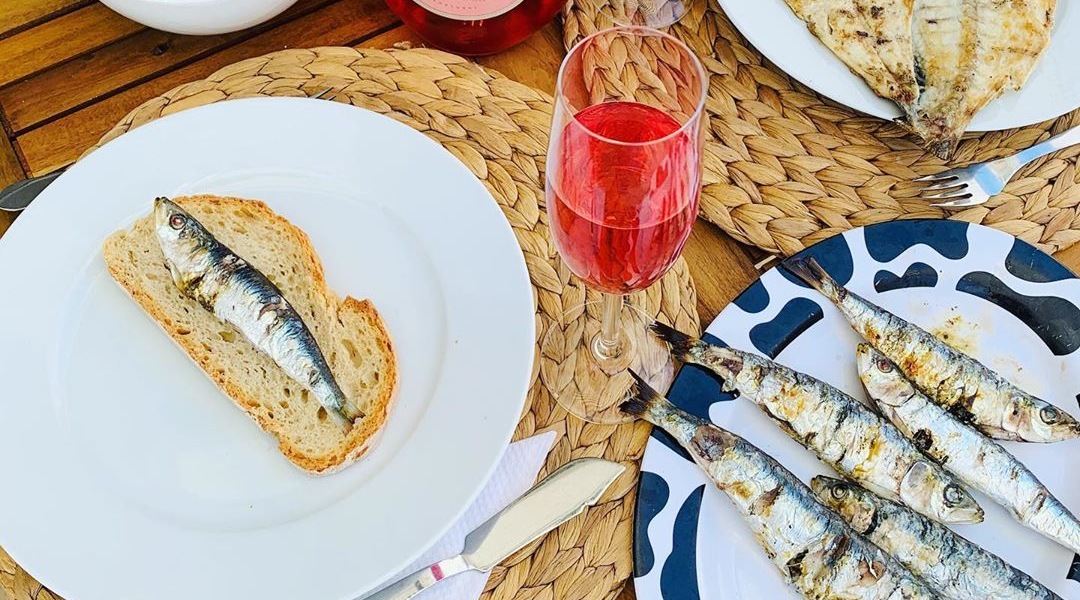 Table of food in Portugal with sardines, bread and wine